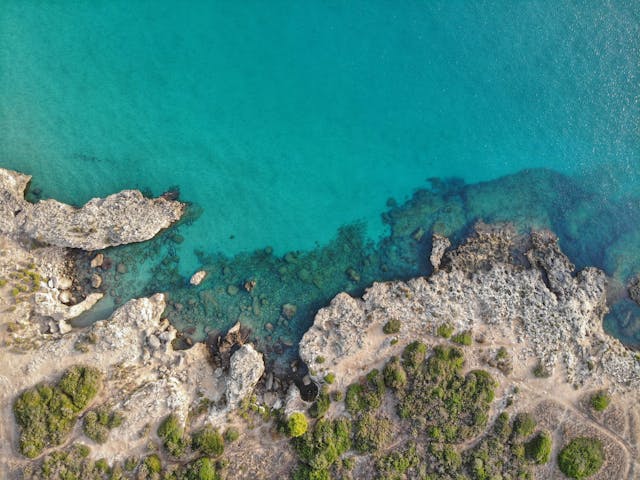 Vista aerea di una costa rocciosa in Sicilia con acque turchesi cristalline
